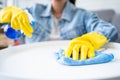 Close-up photo of woman`s hand wearing protecitve yellow rubber gloves cleaning table, holding spray bottle and using microfiber Royalty Free Stock Photo