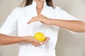 Close up photo of woman`s hands in circle with lemon in a white robe