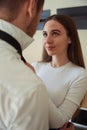 Smiling female looking at man and tying tie