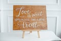 The close-up photo of the wooden plaque with the signs Love to the wedding standing on white background.