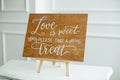 The close-up photo of the wooden plaque with the signs Love to the wedding standing on white background.