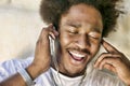 Close up photo of young african american man with eyes closed enjoying music through earphones Royalty Free Stock Photo