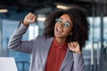 Close-up photo of a young African-American woman in the office, sitting at the workplace and rejoicing in success Royalty Free Stock Photo