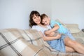 Photo of a young brunette and a 7-years boy playing with a gray kitten sitting on a sofa in a flat Royalty Free Stock Photo