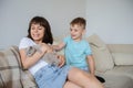 Photo of a young brunette and a 7-years boy playing with a gray kitten sitting on a sofa in a flat Royalty Free Stock Photo