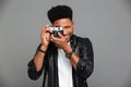 Close-up photo of young cheerful african man looking through retro cameras objective while taking photo Royalty Free Stock Photo