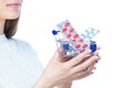 Close up photo of a young female hands holding a small shopping cart full of pills, tablets, capsules and medicine