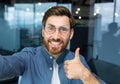 Close-up photo. A young freelancer man, a blogger in glasses, talks to the camera, smiles, shows a super hand, records a Royalty Free Stock Photo