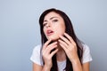 Close up photo of young girl squeezing out a pimple on her chin isolated on gray background copy-space. Close up front view photo