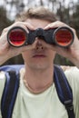 Close-up of young man looking through binoculars in forest