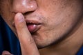 Close Up photo of a young man with silent quiet gesture with finger.