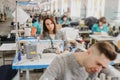 photo of a young man and other seamstresses sewing with sewing machine in a factory