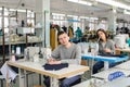 photo of a young man and other seamstresses sewing with sewing machine in a factory