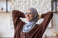 Close-up photo. Young muslim woman freelancer in hijab sitting at table at home after working day using laptop. She Royalty Free Stock Photo