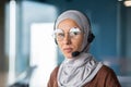 Close-up photo. Young Muslim woman in hijab and headset, helpline and call center consultant sitting in office at desk Royalty Free Stock Photo