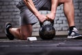 Close-up photo of young sportsman while crouching on a one leg and holding kettlebell against brick wall. Royalty Free Stock Photo