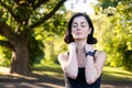 Close-up photo of young tired woman doing sports and exercising outdoors, standing exhausted with closed eyes, holding Royalty Free Stock Photo