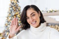 Close-up photo of a young woman talking to the camera on the phone, filming a blog, waving and smiling. Standing at home Royalty Free Stock Photo