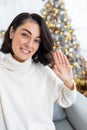 Close-up photo of a young woman talking to the camera on the phone, filming a blog, waving and smiling. Standing at home Royalty Free Stock Photo