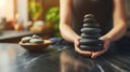 Close-up of hands stacking black stones in a spa-like setting with natural light Royalty Free Stock Photo