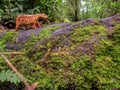 Close-up photography of a handcrafted wooden animal figurine on a moss coverd trunk