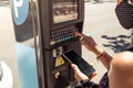 Close up photography of woman using parking meter machine with the smartphone