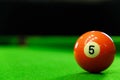 Close-up photos of billiard ball, number 5 and green floor