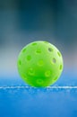 Close up of a pickleball on pickleball blue court line