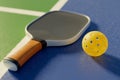 Close-up of a pickleball racket and ball lying on the court line