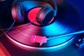 Close-up of a pickup head, black headphones on a vinyl record, colored lights, analogue retro music concept, audio experience, Royalty Free Stock Photo
