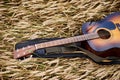 Close-up picture of acoustic guitar lying on wheat field. Travel musician in countryside. Musical instrument