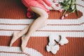 Close-up picture of beautiful woman legs. Tanned woman legs near flowers and slippers. Indoor overhead photo of a girl