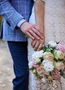 Close-up picture of bride`s and groom`s hands, holding each other and beautiful white and pink flower rose bouquet. Close-up Royalty Free Stock Photo