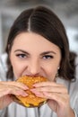 Close up picture of a dark-haired woman eating a burger Royalty Free Stock Photo
