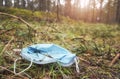 Close up picture of a discarded disposable medical face mask in the forest, selective focus