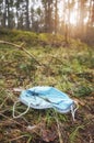 Close up picture of a discarded disposable medical face mask in the forest, selective focus