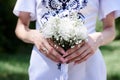 Close-up picture of female hands holding white tender flower bouquet. Young skinny bride on wedding day in summer. Traditional