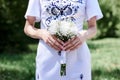 Close-up picture of female hands holding white tender flower bouquet. Young skinny bride on wedding day in summer. Traditional