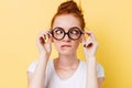 Close-up picture of funny ginger woman in eyeglasess showing grimace