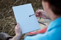 Close-up picture of hands of male artist, holding empty white canvas on wheat field in summer. Painting workshop in rural Royalty Free Stock Photo