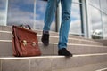 Close-up of a man on stairs outside. Businessman with a briefcase on a blurred stairs background. Career growth concept. Royalty Free Stock Photo