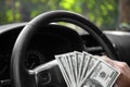 Close-up of american dollars on a wheel. A man driving with money on a car background. Investment and savings concept. Royalty Free Stock Photo