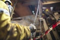 Rigger wearing helmet safety glass using hand commencing pulling a heavy duty chains block