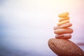 Balance, relaxation and wellness: Stone cairn outside, ocean in the blurry background. Sunshine Royalty Free Stock Photo