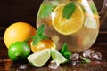 Close-up of a new citrus drink preparation. Green lime, mint and juicy orange with crushed ice on a wooden background. Royalty Free Stock Photo