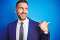 Close up picture of young handsome business man over blue  background smiling with happy face looking and pointing to the Royalty Free Stock Photo