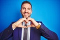 Close up picture of young handsome business man over blue isolated background smiling in love showing heart symbol and shape with Royalty Free Stock Photo