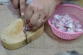 Close-up pictures of people. The chefs are slicing red onions, small vegetables, herbs on a wooden cutting board. Royalty Free Stock Photo