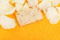 Close-up, a piece of handmade soap on scattered orange bath salts in the form of small balls, surrounded by white rose petals Royalty Free Stock Photo