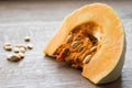 Close-up of a piece of orange pumpkin and seeds, indoors, wooden